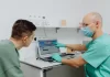 Czy można rozłożyć leczenie stomatologiczne na raty bez dodatkowych kosztów Dentysta omawia z pacjentem plan leczenia z wykorzystaniem laptopa.