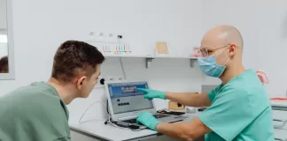 Dentysta omawia z pacjentem plan leczenia z wykorzystaniem laptopa.