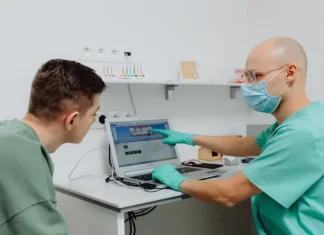 Czy można rozłożyć leczenie stomatologiczne na raty bez dodatkowych kosztów Dentysta omawia z pacjentem plan leczenia z wykorzystaniem laptopa.