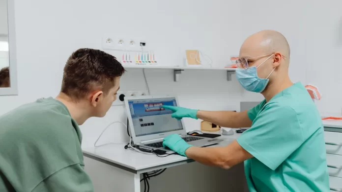 omowienie-kosztow-leczenia-u-dentysty Dentysta omawia z pacjentem plan leczenia z wykorzystaniem laptopa.